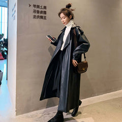Model wearing Autumn New Leather Trench Slim-fit Leather Coat in black, styled with a white top and handbag.