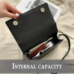 Small PU leather crossbody bag open showcasing internal capacity with sleek design and organized items.